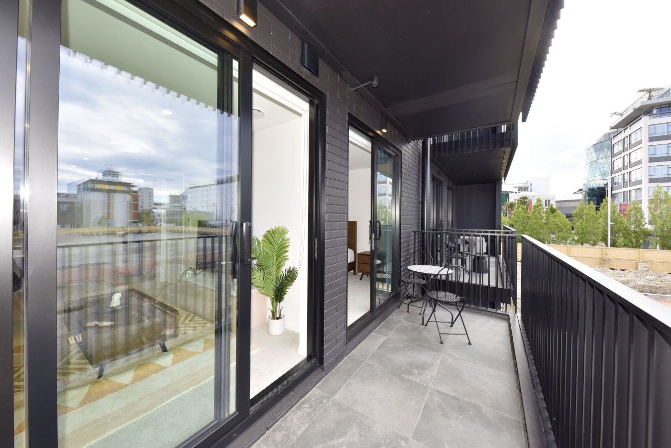 A modern balcony with a glass door, a small table, and a potted plant.