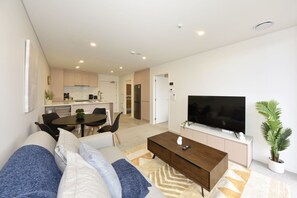 Ein modernes Wohnzimmer mit Sofa, Couchtisch und Flachbildfernseher.