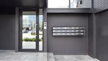 A modern building entrance with a glass door and a wall-mounted mailbox.