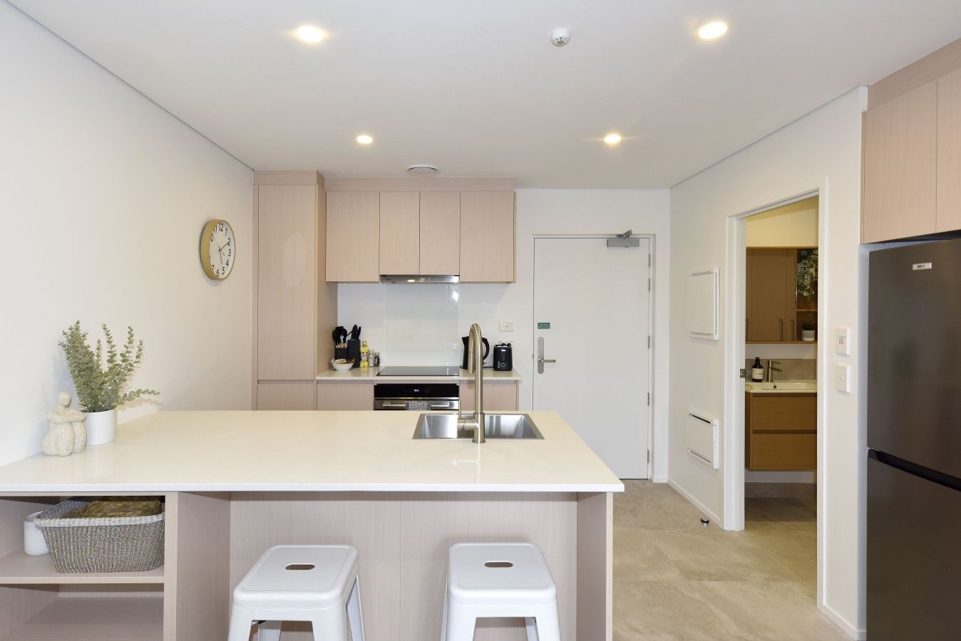 A modern kitchen with a central island, stainless steel appliances, and a clock on the wall.