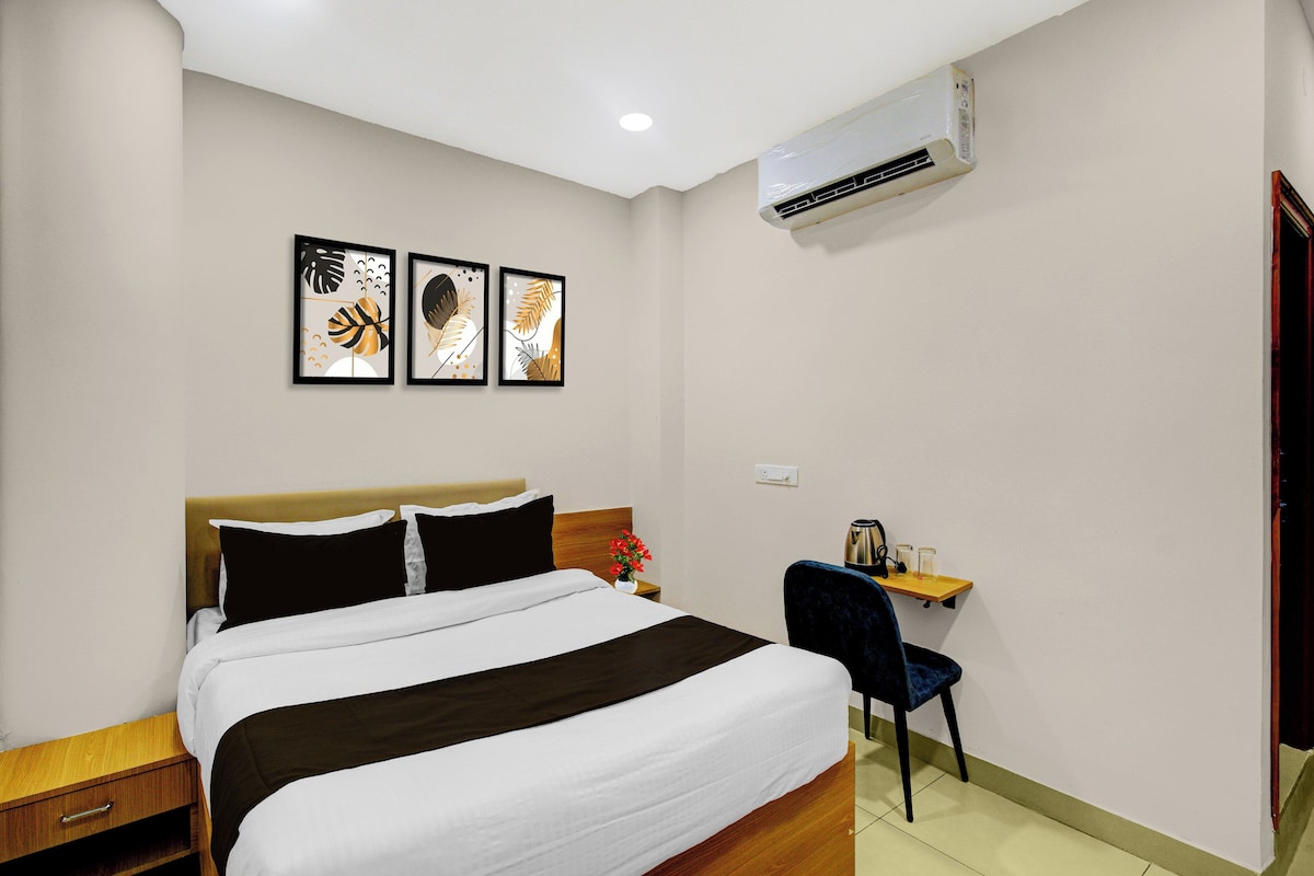 A hotel room with a bed, a desk, a chair, and wall art.