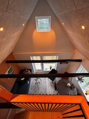A high-ceilinged room with a skylight, a staircase, and a view of a living area below. - Klaksvíksvegur 64G (Klaksvík)