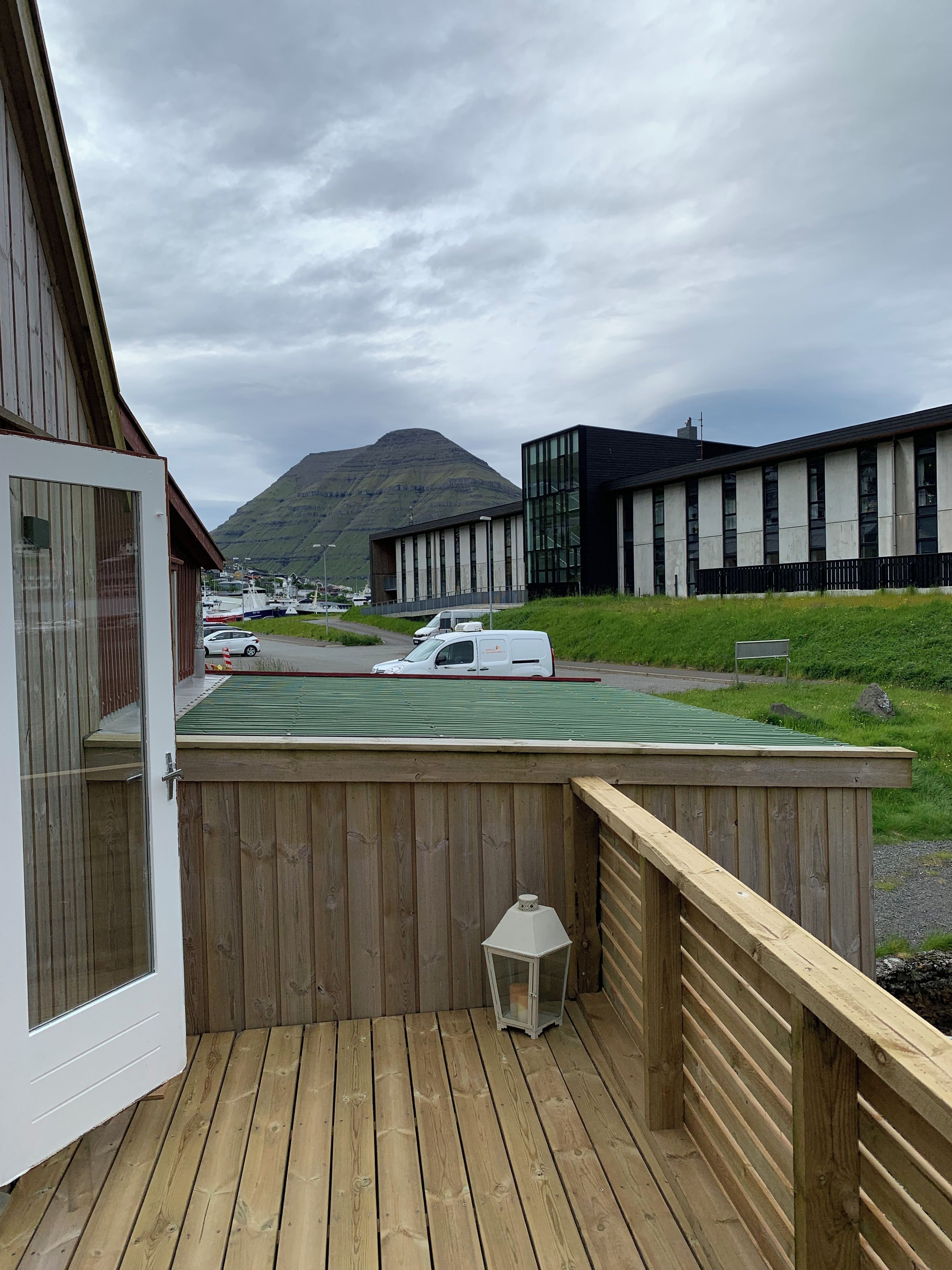 Eine Holzterrasse mit Blick auf einen Berg und moderne Gebäude im Hintergrund.