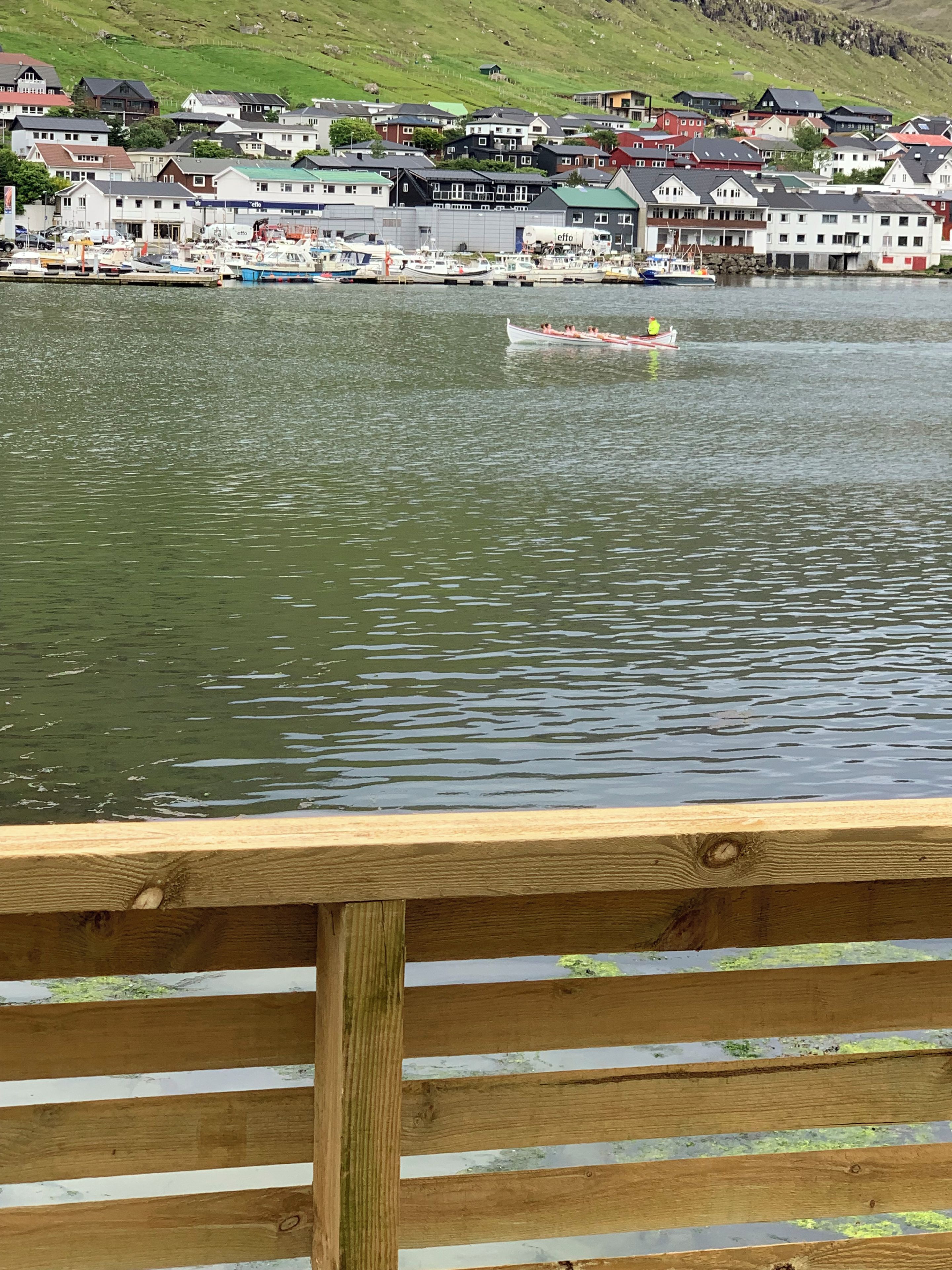Un muelle de madera que conduce a un lago tranquilo con casas al fondo.