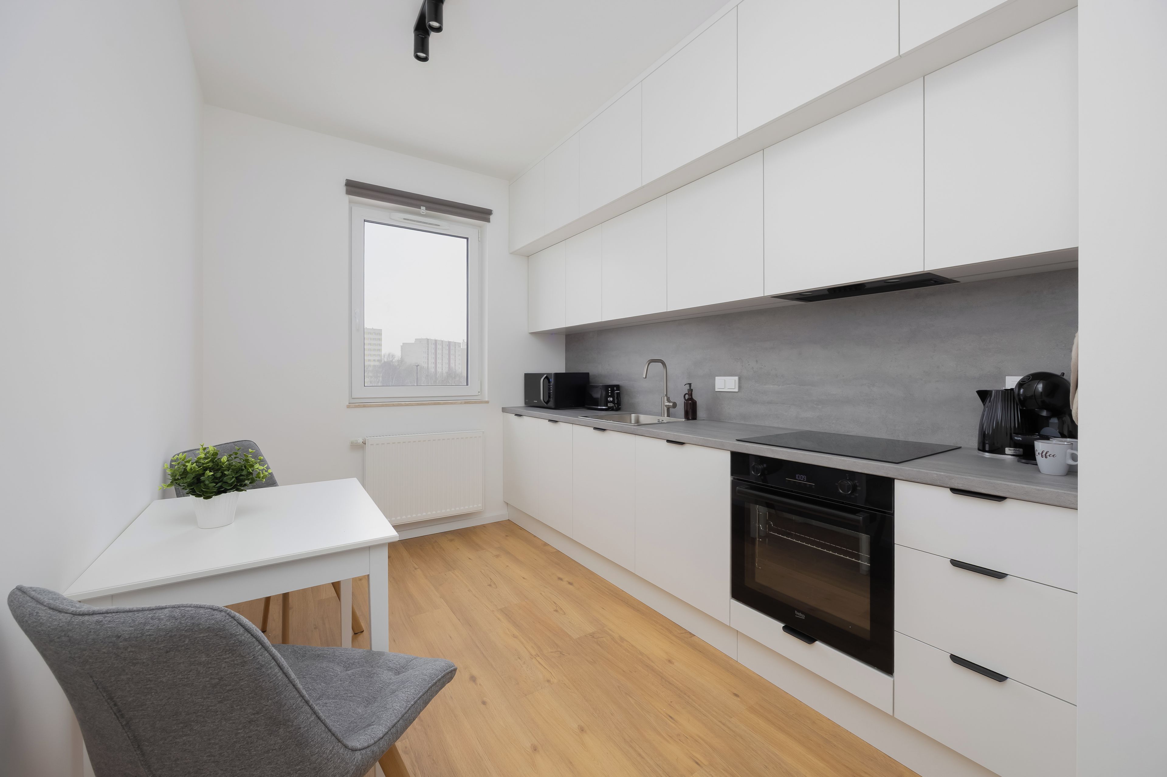 Een moderne keuken met witte kastjes, een zwart aanrechtblad en een inbouw vaatwasser.