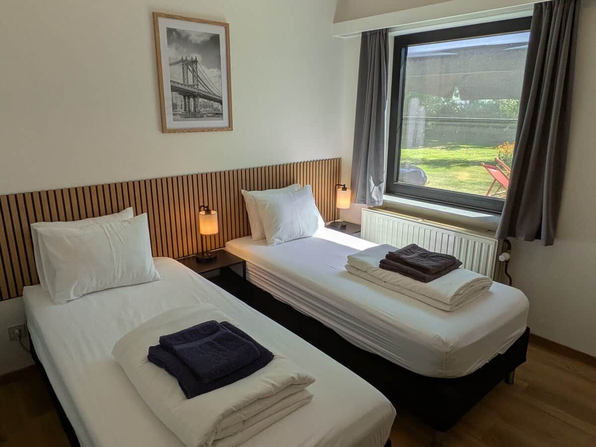 A hotel room with two beds, a window with a view, and a framed picture on the wall.