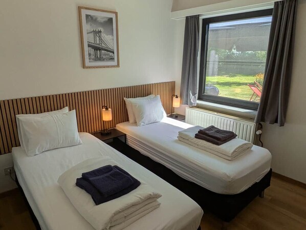 A hotel room with two beds, a window with a view, and a framed picture on the wall.