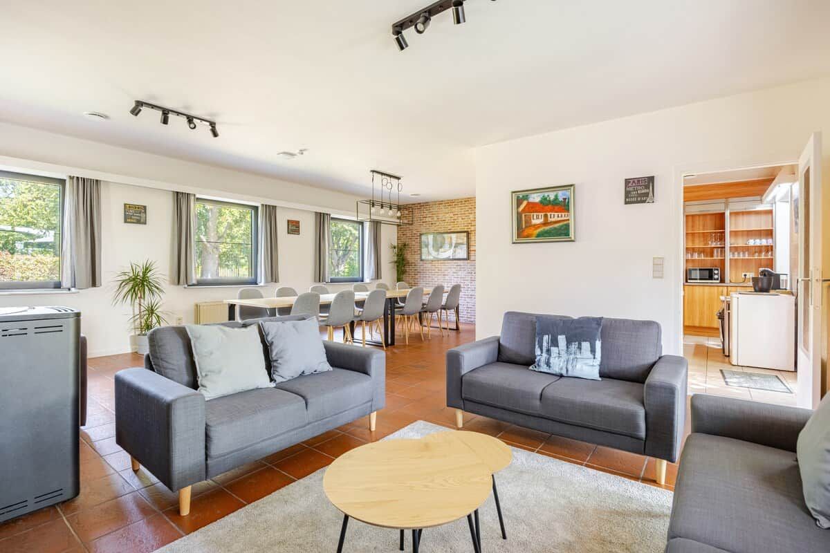 A modern living room with two sofas, a coffee table, and a dining area with chairs and a table.