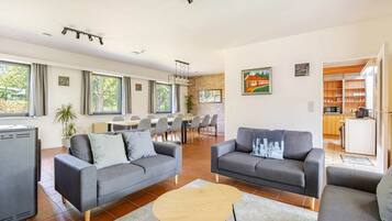 A modern living room with two sofas, a coffee table, and a dining area with chairs and a table.