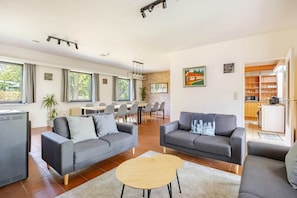 A modern living room with two sofas, a coffee table, and a dining area with chairs and a table.