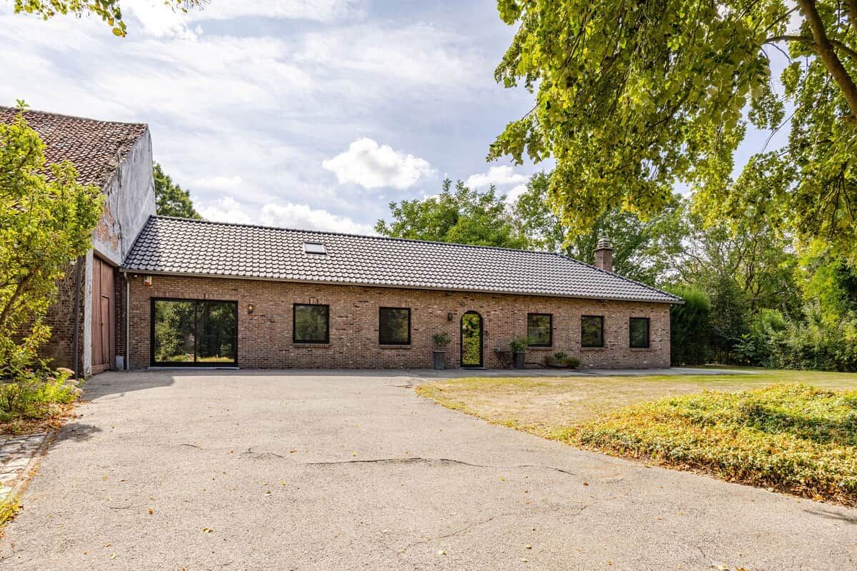 A brick building with a tiled roof, a large open driveway, and a well-maintained lawn.