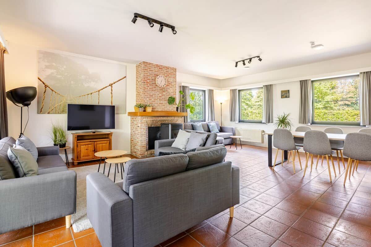 Een moderne woonkamer met een open haard, een televisie en een eethoek met stoelen.