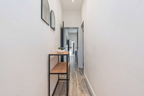Un couloir étroit avec une table en bois et un miroir accroché au mur.