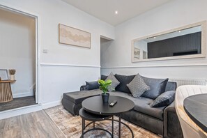 Un salon moderne avec un canapé gris, une table basse ronde et une plante en pot.