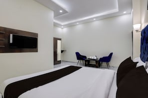 A hotel room with a bed, a desk with two chairs, a television mounted on the wall, and a mirror. - Super Hotel O Clock Tower Dehradun (Dehradun)