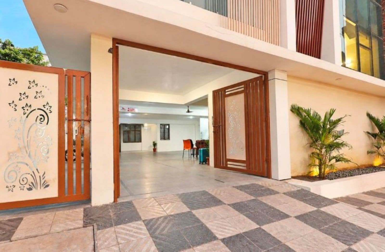 A hotel entrance with a checkered floor, a decorative gate, and a seating area with chairs.