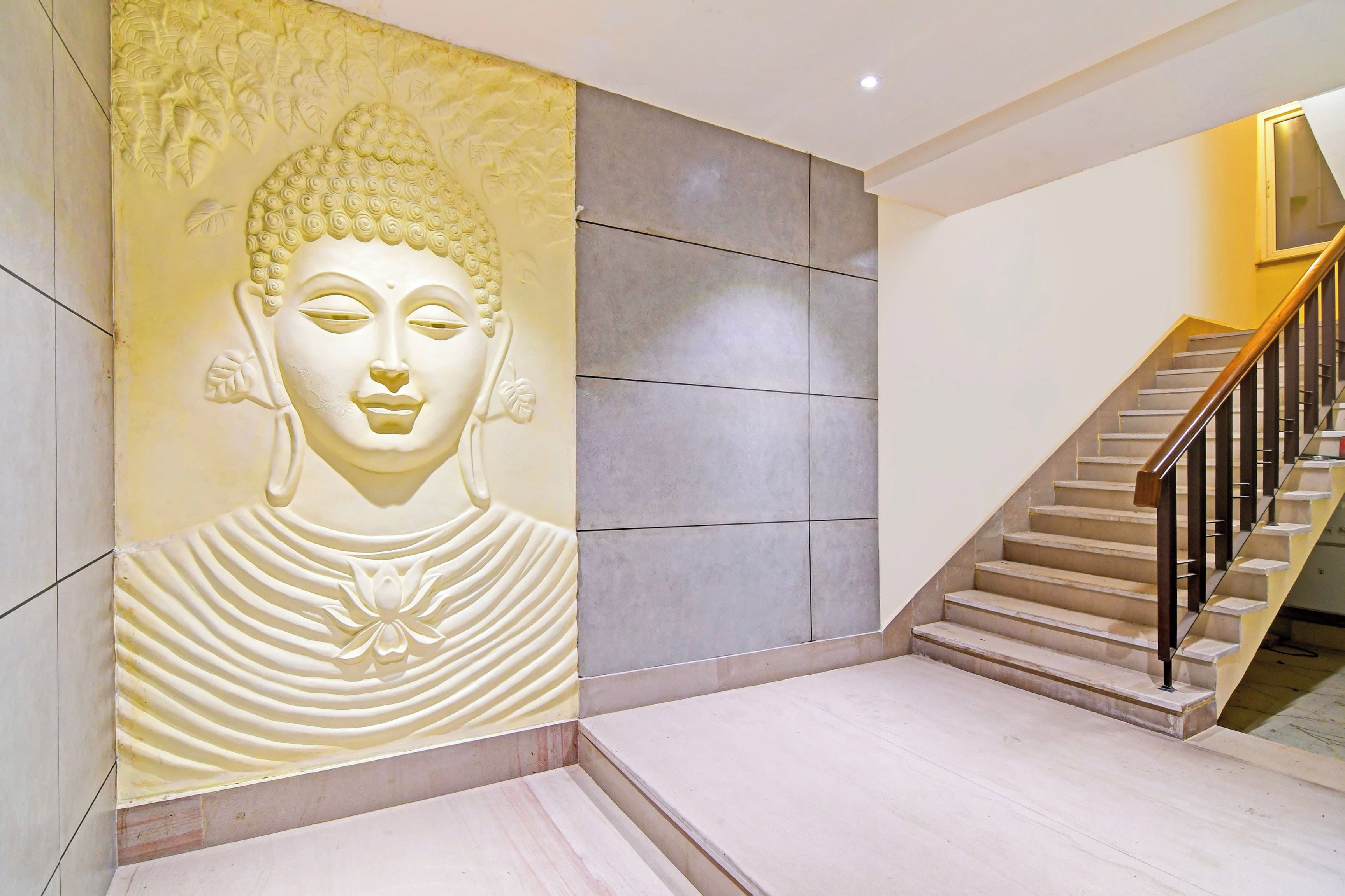 A staircase with a handrail and a wall with a Buddha statue.
