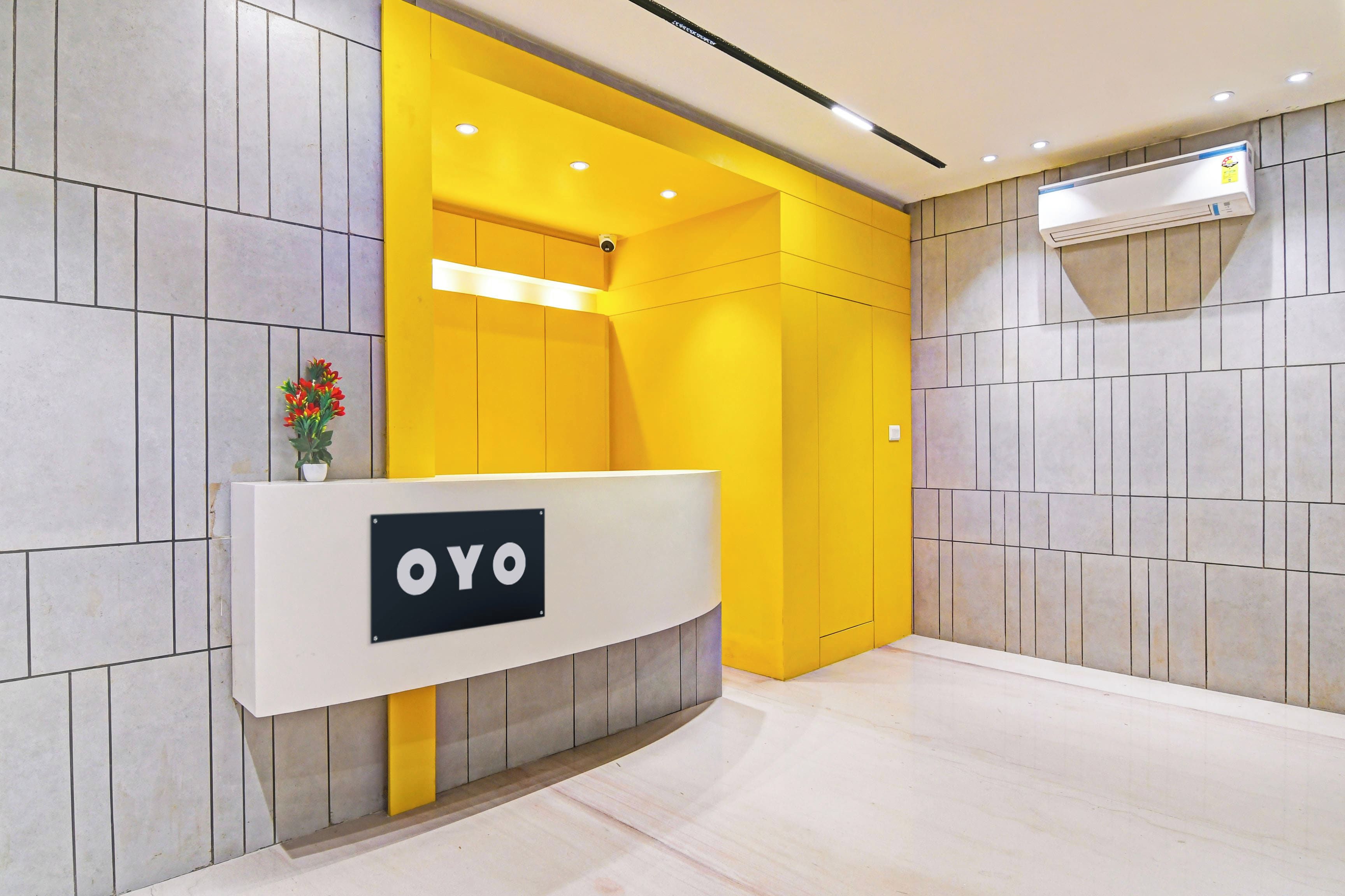 A reception area with a reception desk labeled 'OYO' and a wall-mounted air conditioning unit.