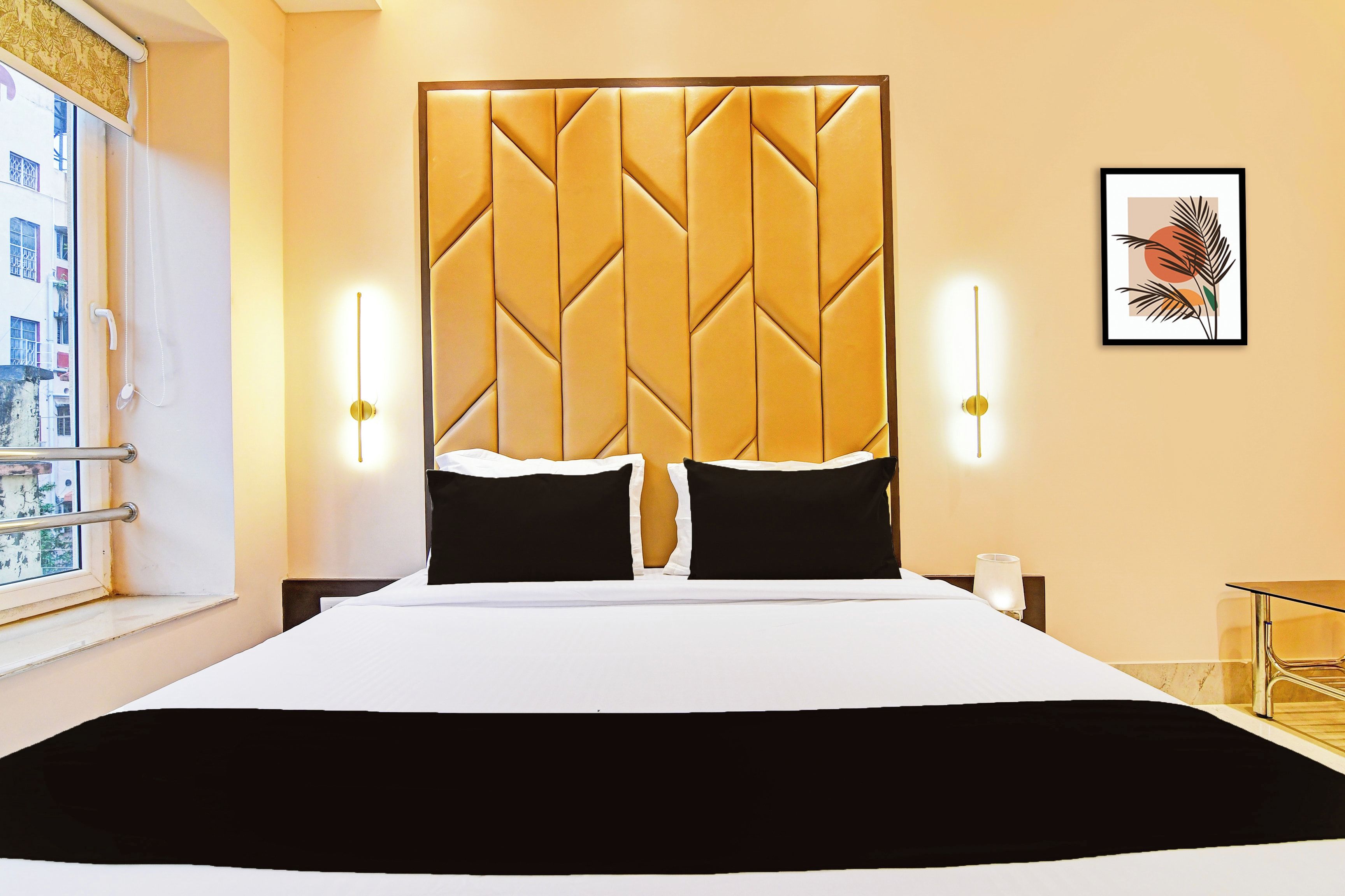 A hotel room with a large bed, two bedside lamps, a window with a view, and a framed picture on the wall.
