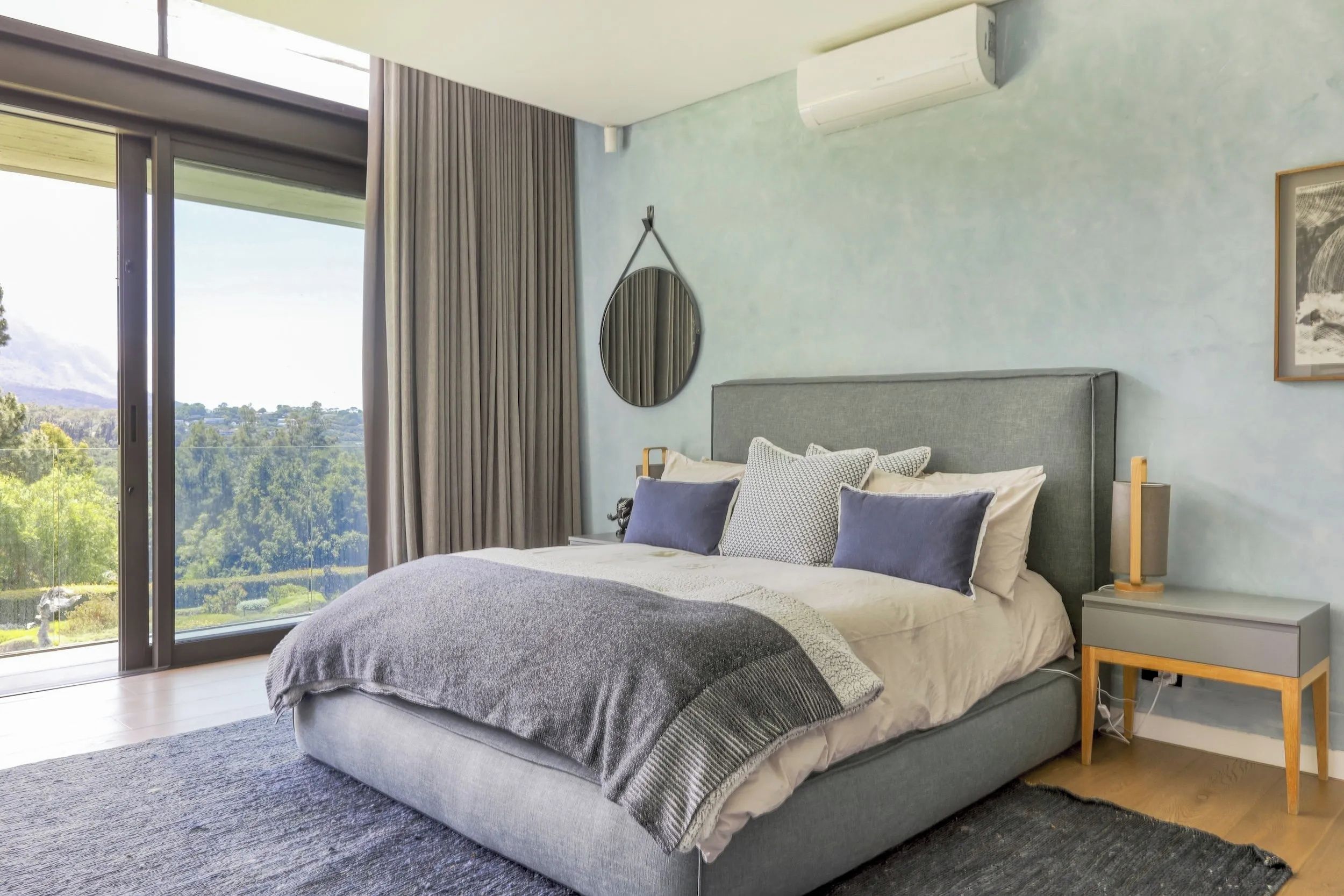 Una camera da letto moderna con un letto grande, vista sull'esterno e condizionatore d'aria a muro.