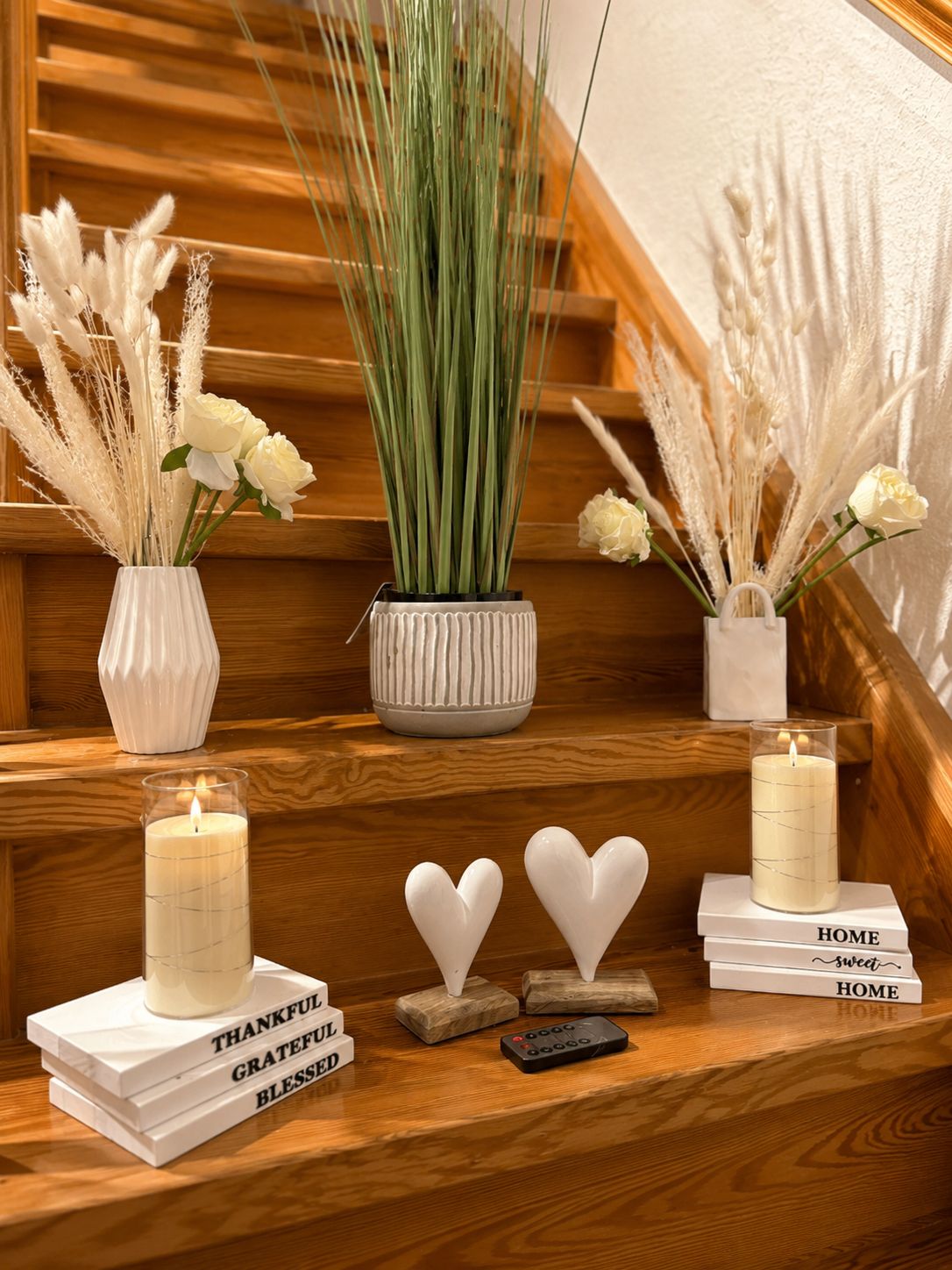 A staircase with decorative elements including white candles, a vase with green plants, and white flowers.