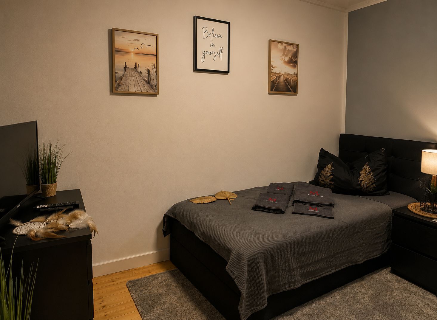 Une chambre à coucher avec un lit, un bureau, une télévision et des œuvres d’art murales.