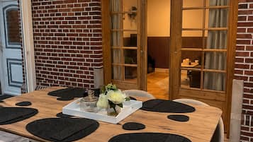 Un coin repas avec un mur en briques, une table en bois et deux chaises.