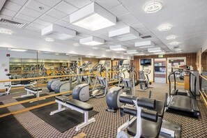 A gym with various exercise equipment, a mirrored wall, and a patterned carpet. - 2BR Winter Wonderland (Park City)