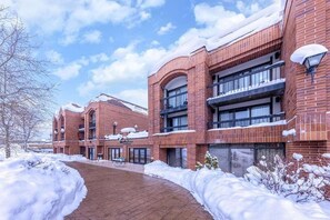 A multi-story building with brick exterior and large windows, surrounded by snow. - 2BR Winter Wonderland (Park City)