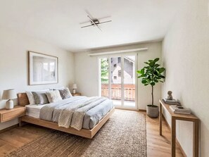 A bedroom with a bed, bedside tables, a ceiling fan, a large window, and a potted plant. - Beautiful And Cozy Apartment by Interhome (St. Moritz)