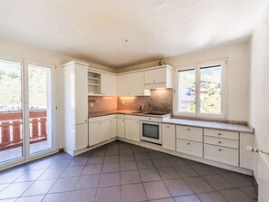 A compact kitchen with white cabinets, a built-in oven, and a window overlooking a backyard. - Beautiful And Cozy Apartment by Interhome (St. Moritz)
