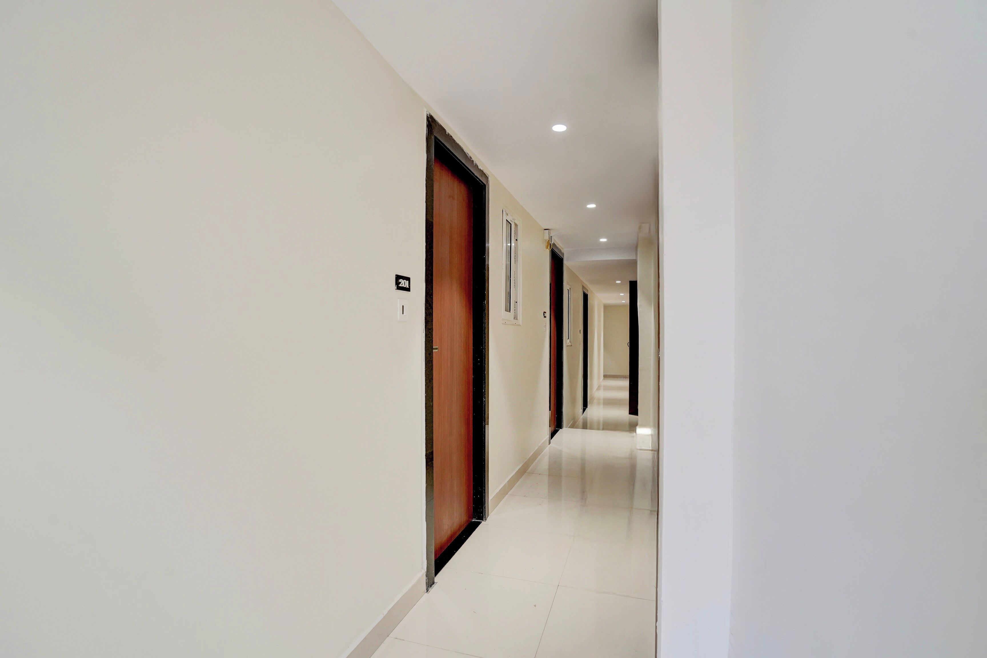 A corridor with doors, numbered signs, and recessed lighting.