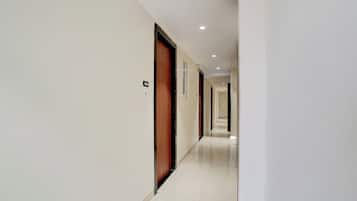 A corridor with doors, numbered signs, and recessed lighting.