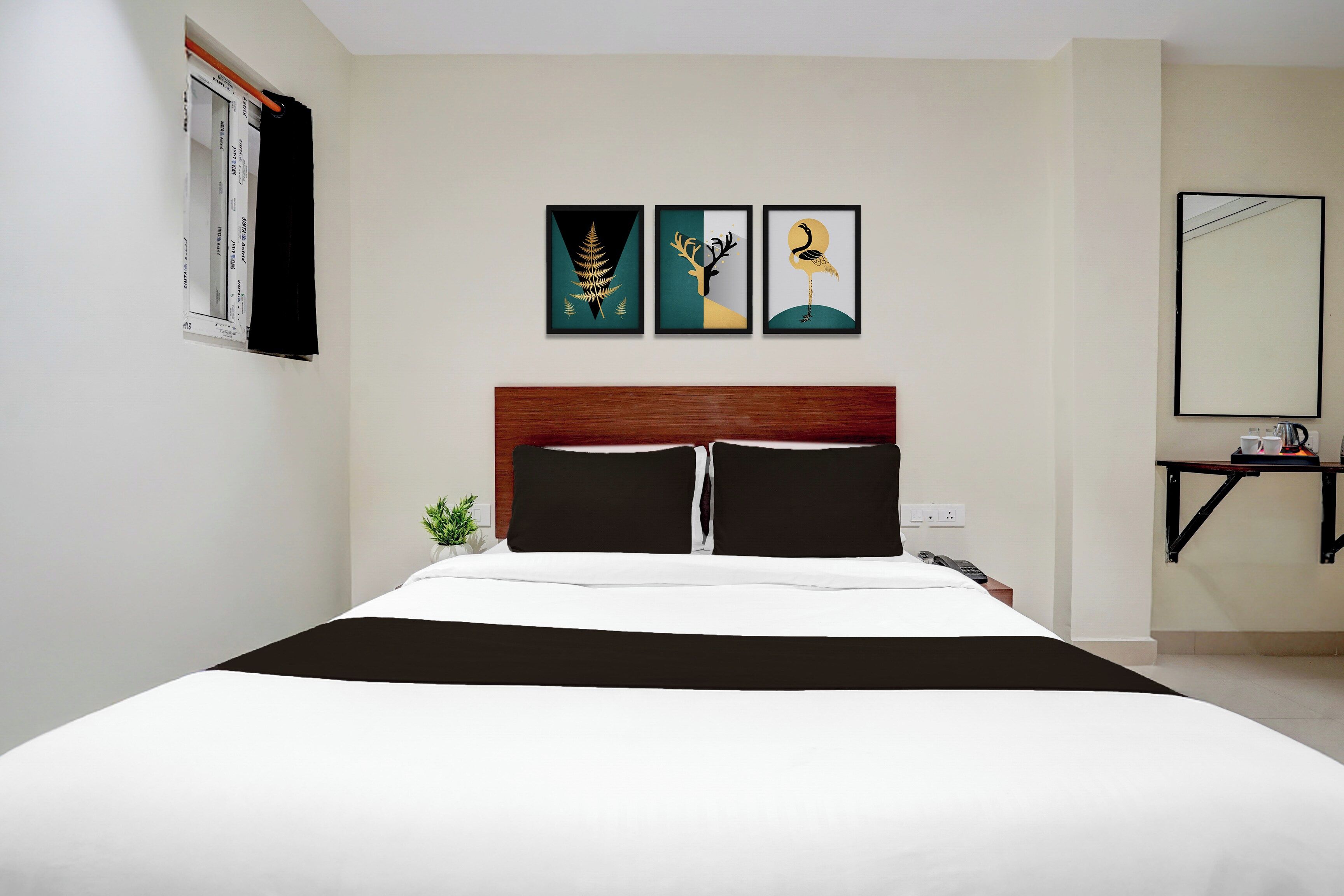 Habitación de hotel con cama, mesita de noche, una pequeña mesa con hervidor y espejo instalado en la pared.
