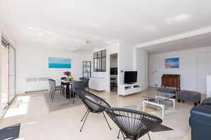 A modern living room with a dining area, a TV, and a wooden cabinet. - 3-Bedroom Apartment with Ocean View Terrace, Parking, 5 min from the Croisette A3B138 (Cannes)