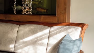 A wooden bench with a plaid cushion and a single blue pillow.