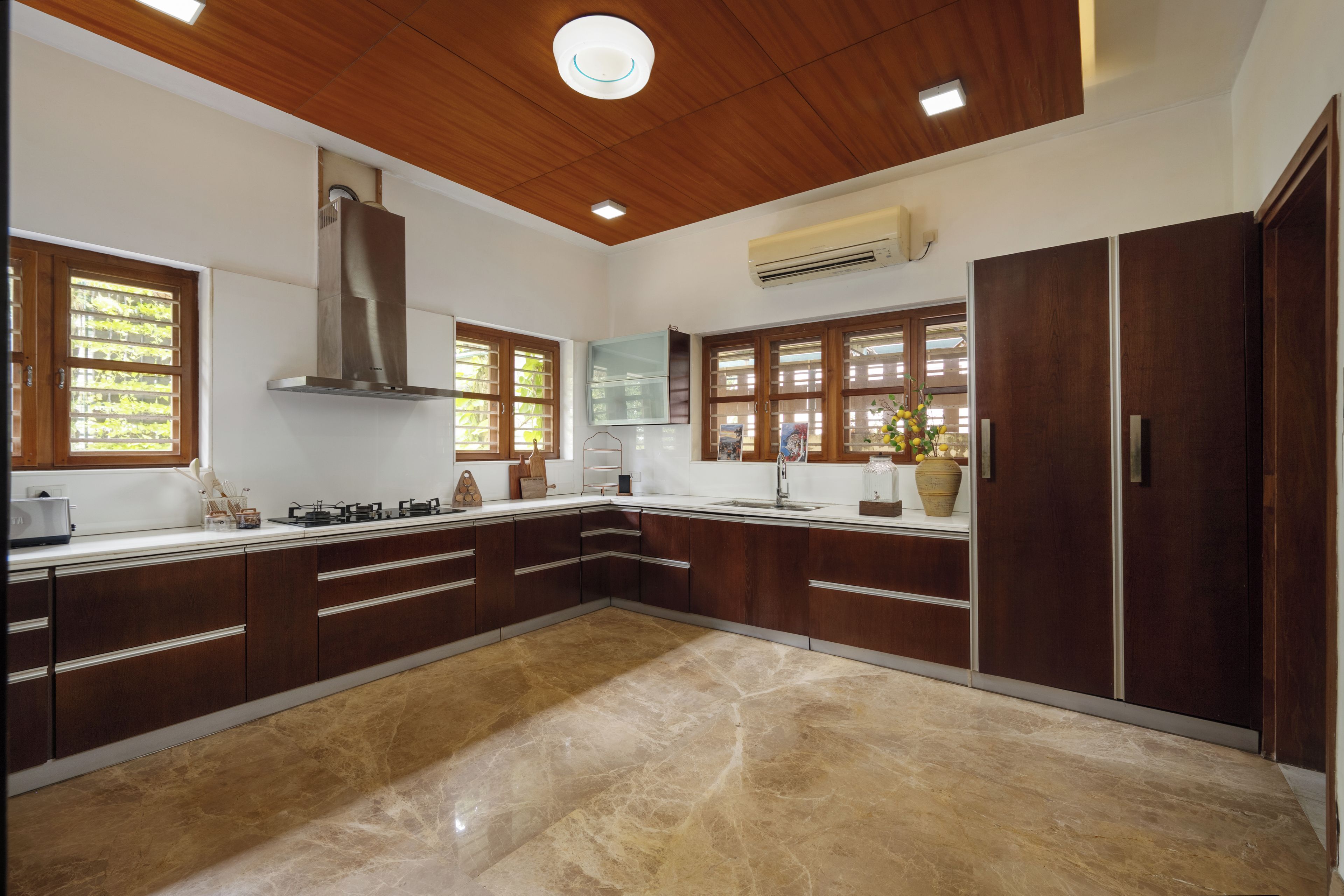 A modern kitchen with wooden cabinets, a central island, and a built-in stove.