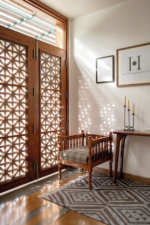 A wooden bench with a patterned cushion, a wall-mounted picture frame, and a decorative candle holder.