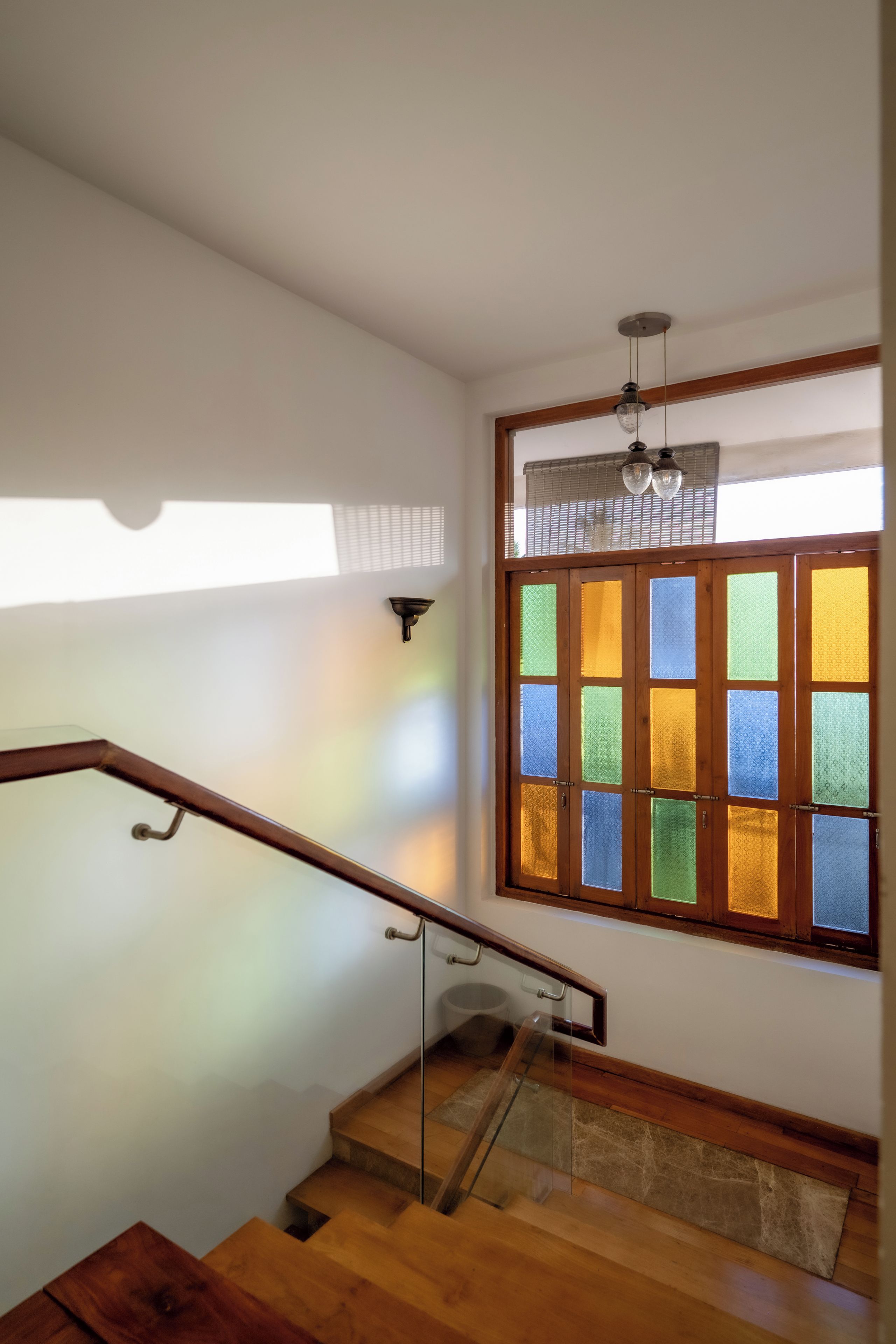 Una escalera de madera con barandilla de vidrio que lleva a una plataforma.
