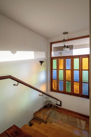 A wooden staircase with a glass handrail leading to a landing.