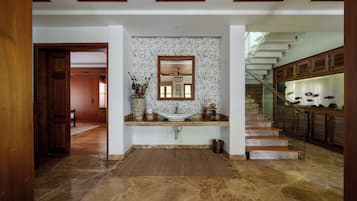 A modern interior with a kitchen island, a large mirror, and a staircase leading to an upper level.