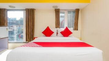 Een hotelkamer met een bed, gordijnen, een raam en uitzicht op de stad.