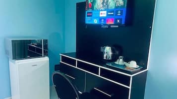 Una stanza con una scrivania nera, un condizionatore d'aria bianco, una televisione a muro e una macchina da caffè sulla scrivania.