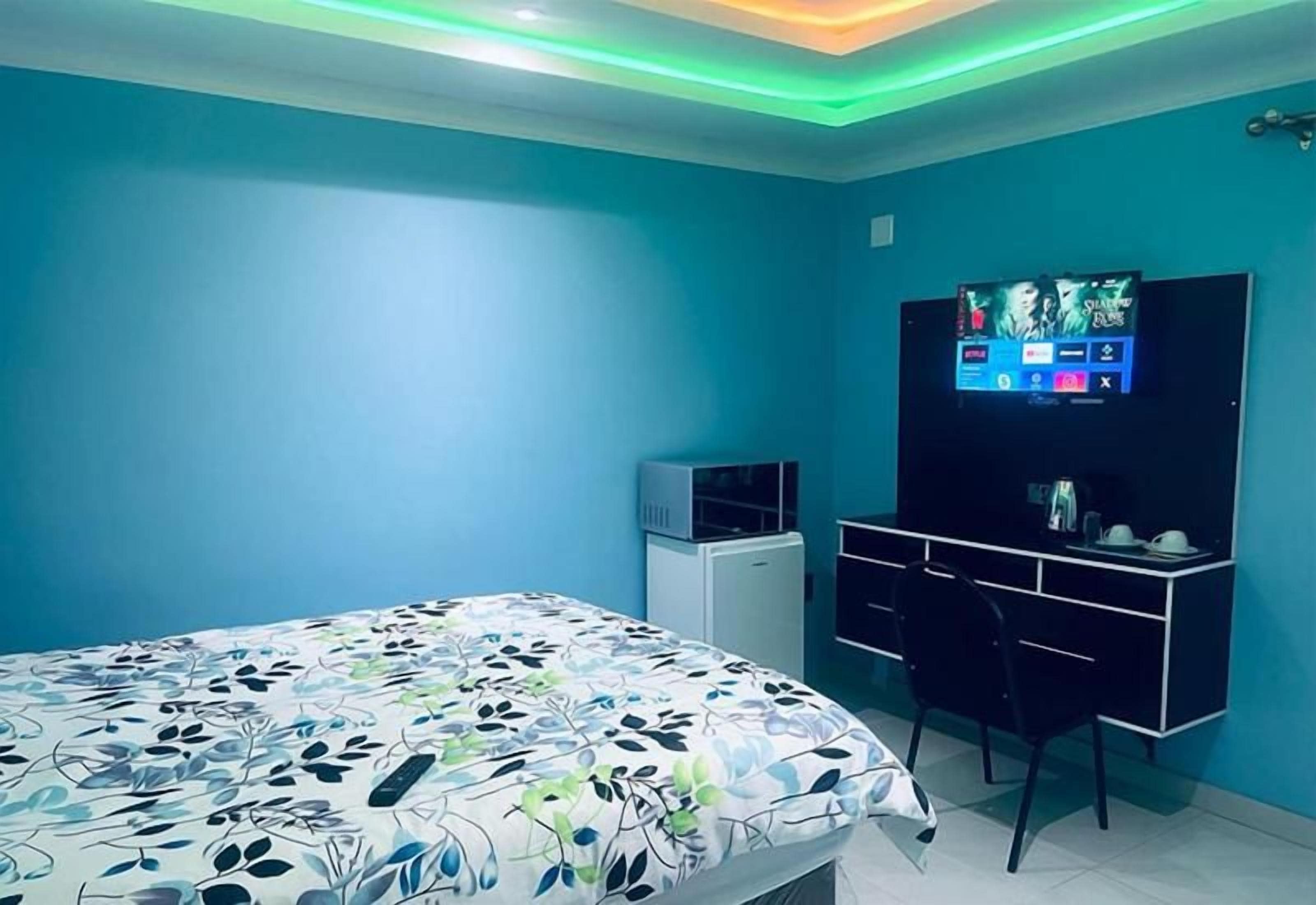 A bedroom with a bed, a desk, and a television.