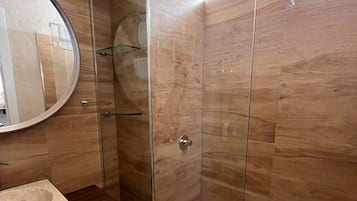 A modern bathroom with a glass-enclosed shower, a wooden vanity, and a round mirror.
