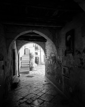 A narrow stone pathway leading through an arched doorway, flanked by buildings with visible windows and doors. - New Listing (Gioia del Colle)