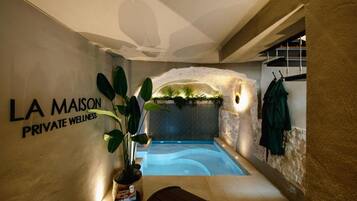 A private wellness area with a spa tub, a potted plant, and a wall-mounted sign reading 'LA MAISON PRIVATE WELLNESS.'