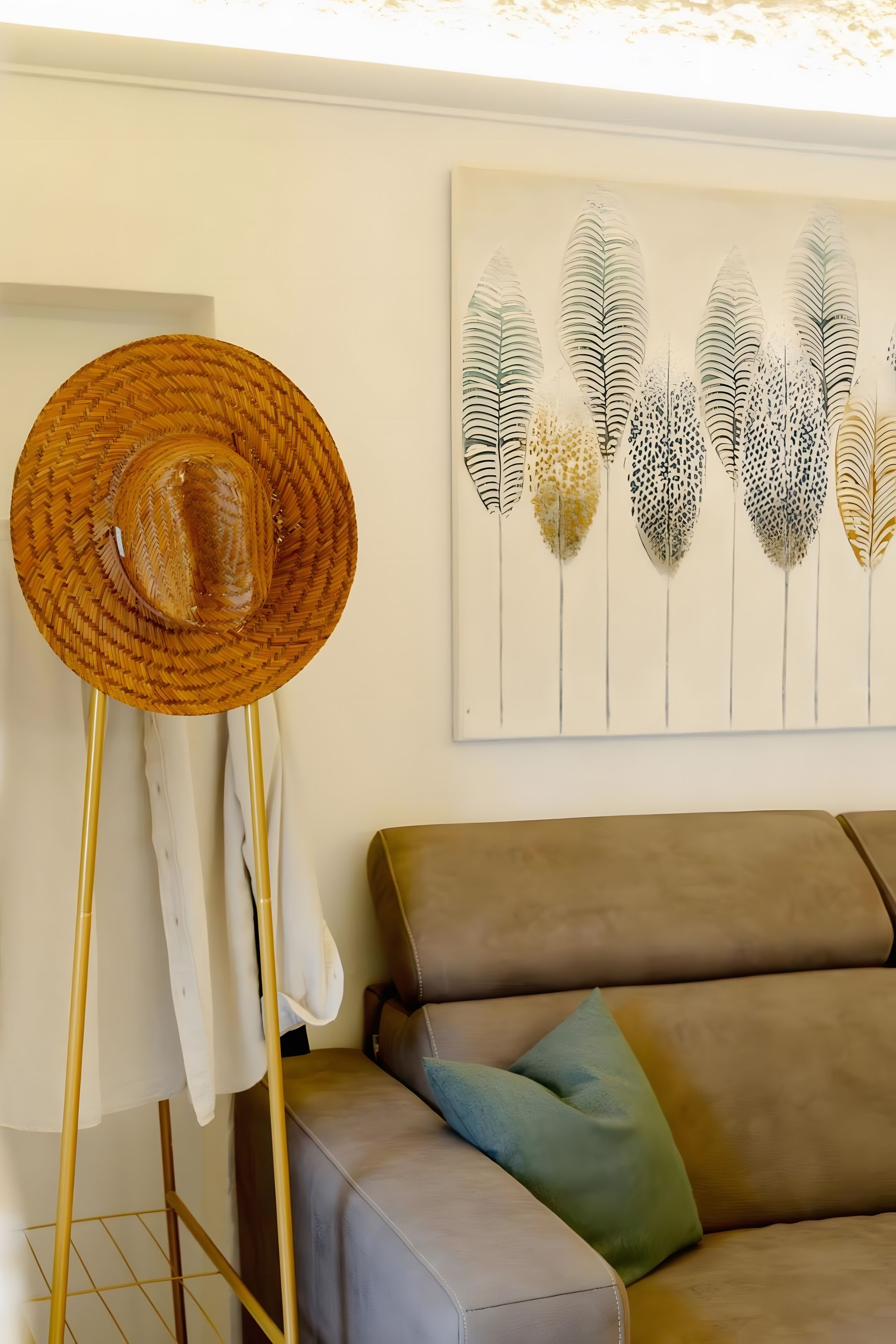 A room with a standing floor lamp, a sofa with cushions, and a wall-mounted artwork.