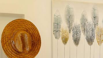 A room with a standing floor lamp, a sofa with cushions, and a wall-mounted artwork.