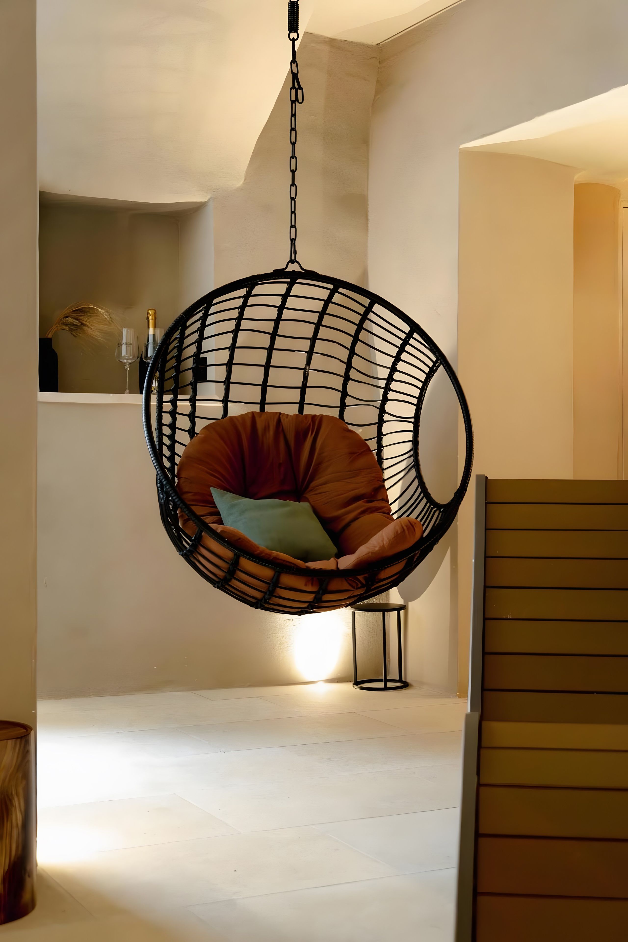 A hanging chair with cushions in a room with a light-colored floor and walls.